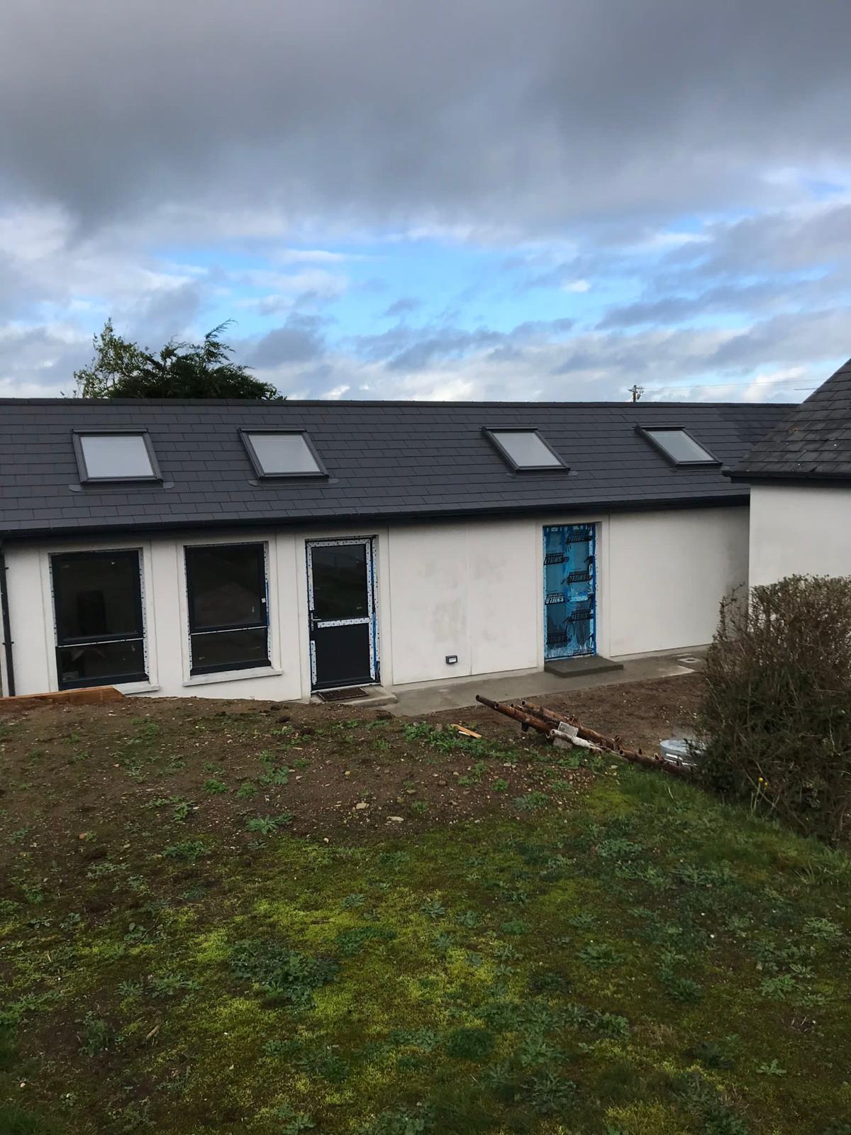 Velux windows and attic conversion exterior view with hill in front of the bungalow